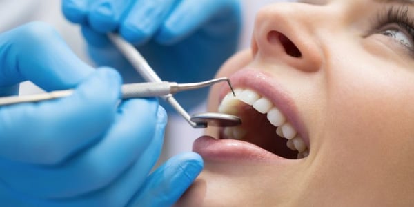 Pessoa-com-a-boca-aberta-e-um-dentista-mechendo-com-intrumentos-cirúrgicos