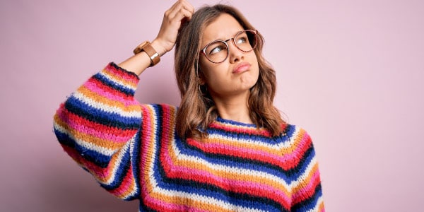 Imagem-de-mulher-loura-usando-óculos-e-blusa-listrada-com-a-mão-na-cabeça-em-pose-de-dúvida