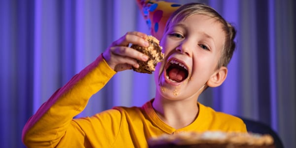 imagem-de-criança-com-a-boca-aberta-comendo-um-pedaço-de-bolo-imagem-de-frases-com-verbos-transitivos-diretos